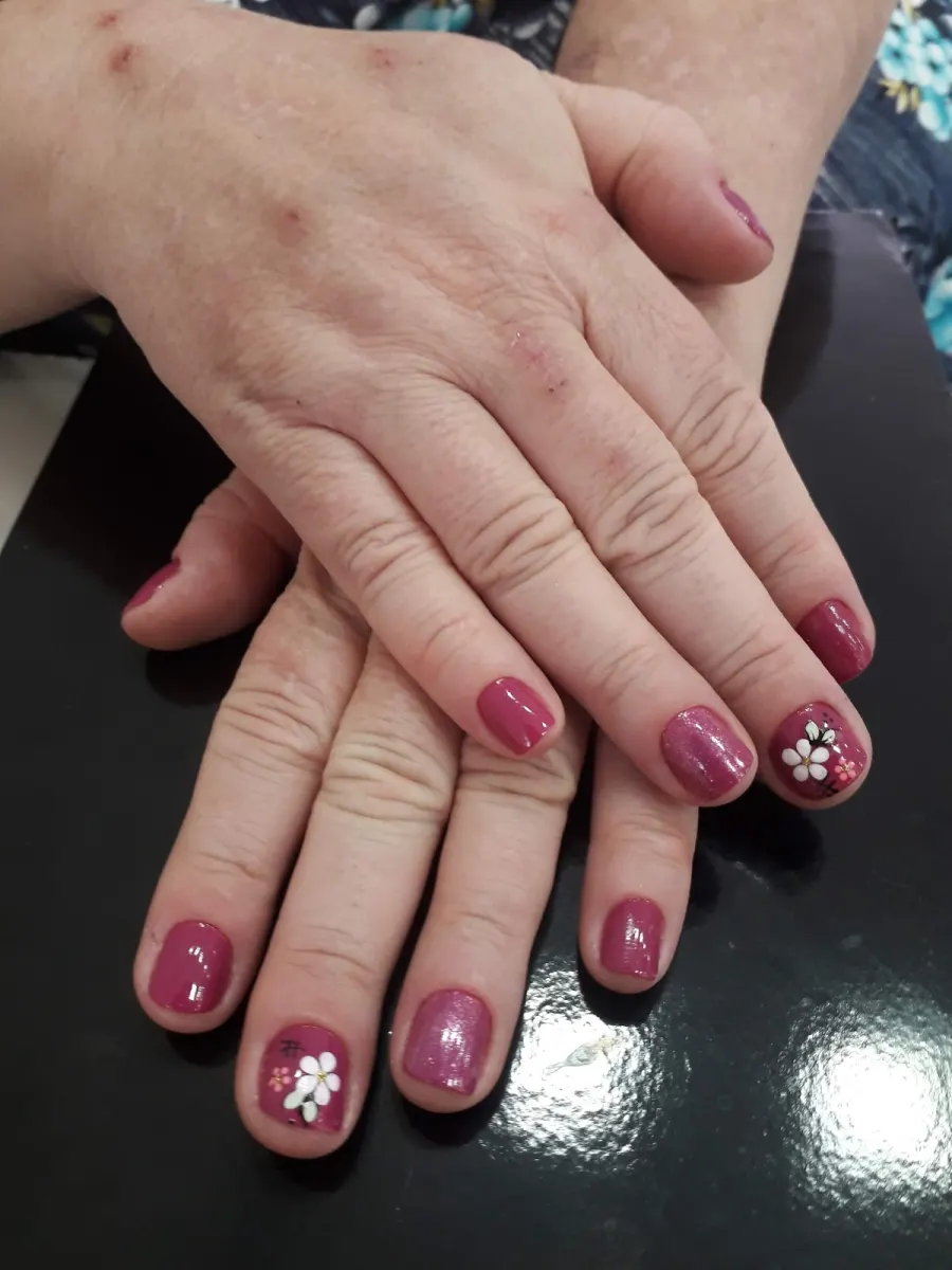 Unhas em tom rosa com nail art de flores