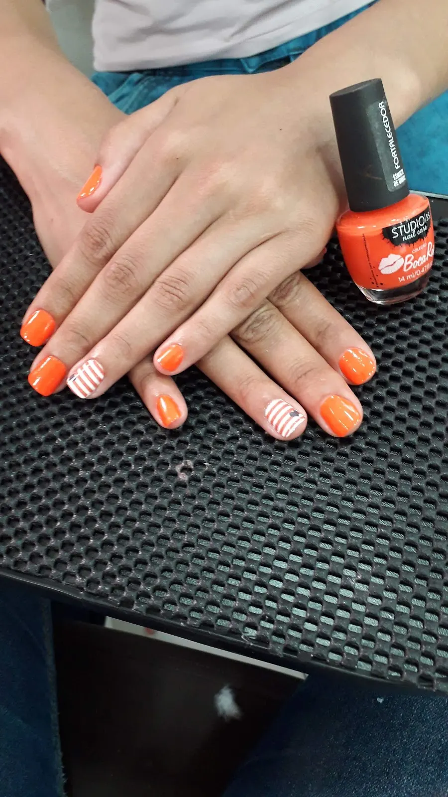 Unhas em esmalte laranja com detalhe listrado